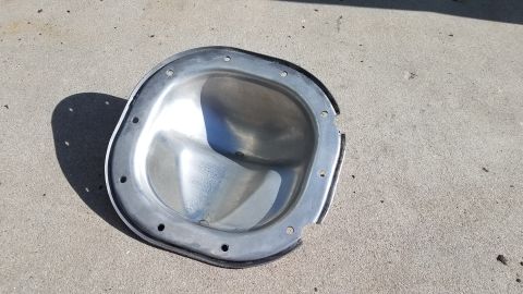 2005 Ford Mustang - A differential cover with a gasket is shown resting on a concrete surface.