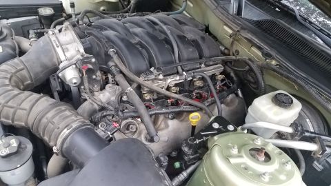 2005 Ford Mustang - The engine bay of a car is shown, with focus on the intake manifold and associated components. Some spark plug wires appear to be disconnec…