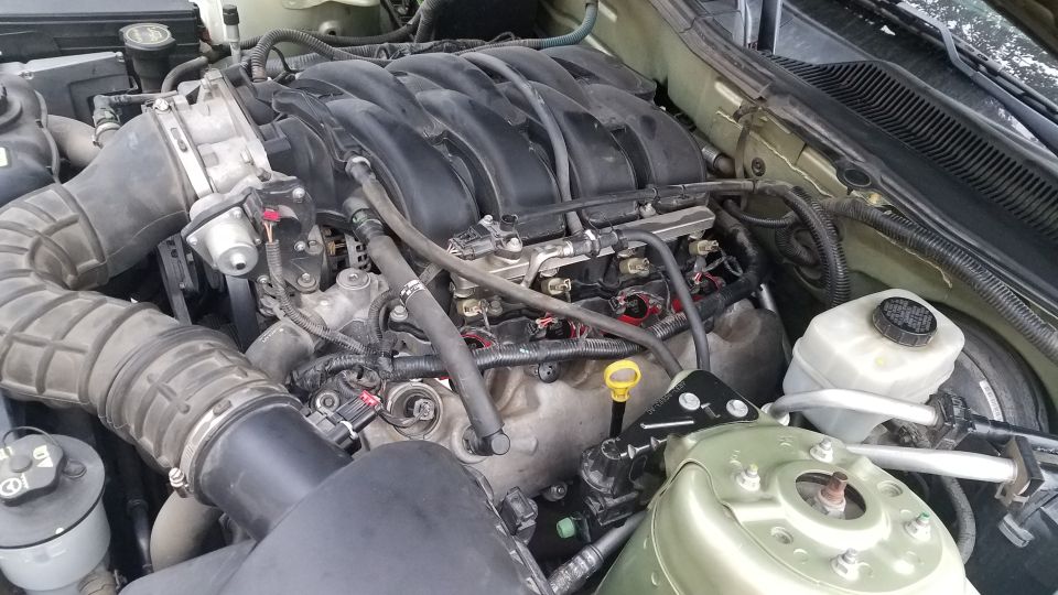 Engine bay of a car, showing the intake manifold, air intake, and brake fluid reservoir. Some spark plug wires are disconnected