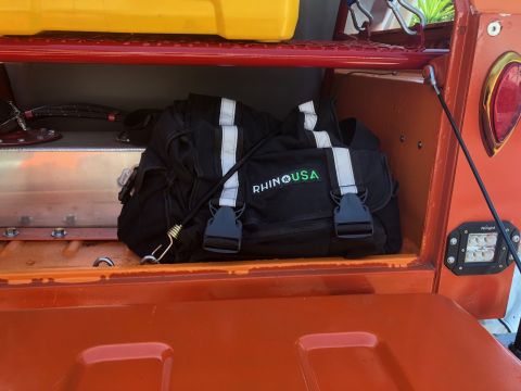 1992 Jeep Wrangler - A black bag with reflective stripes and 'RHINO USA' logo sits in an orange storage compartment.