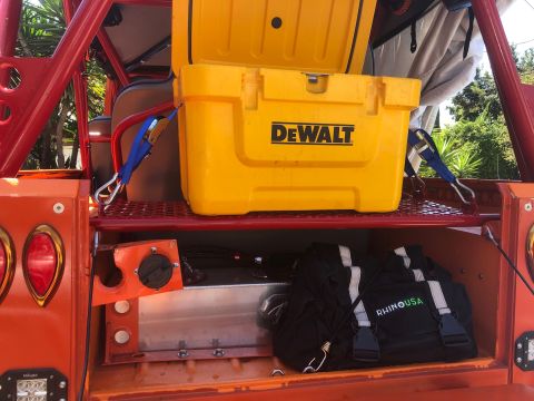 1992 Jeep Wrangler - Rear storage area of an off-road vehicle contains a yellow cooler and a black bag.