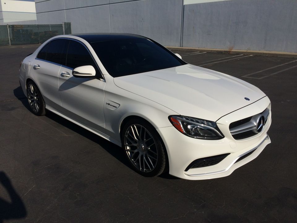 White Mercedes-Benz sedan with a black roof, parked outdoors. The front three-quarter view shows the headlights, grille, and front bumper