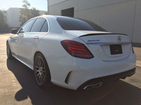 2017 Mercedes-Benz C-Class - A white Mercedes-Benz sedan is parked outside a building, showing its rear profile and distinctive taillights.