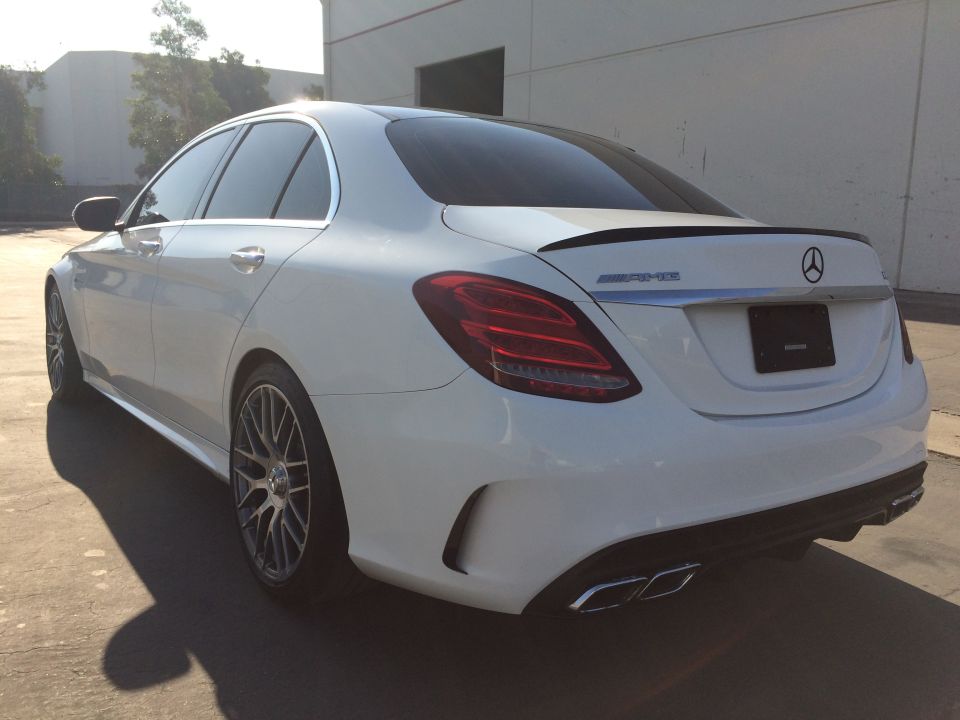 White Mercedes-Benz sedan, rear 3/4 view, with spoiler and quad exhaust tips