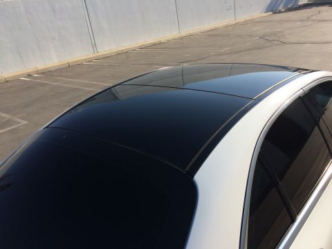 2017 Mercedes-Benz C-Class - A white car's roof with a large black panoramic sunroof is visible against a concrete wall and parking lot.