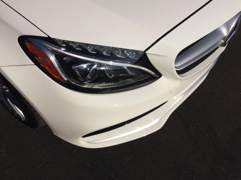 2017 Mercedes-Benz C-Class - Front corner view of a white Mercedes-Benz, highlighting the headlight and grille design. This appears to be a 2017 model.