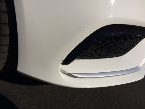 2017 Mercedes-Benz C-Class - A close-up view of the front bumper of a white vehicle, highlighting its grille and trim details.