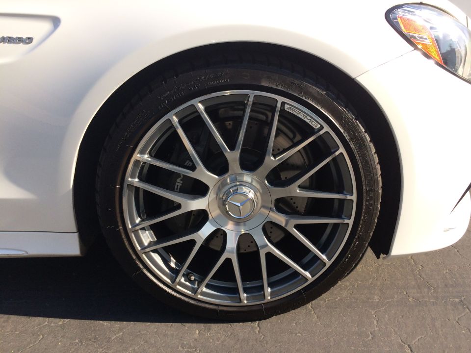 White car front wheel with AMG brake caliper and Mercedes-Benz logo wheel cap