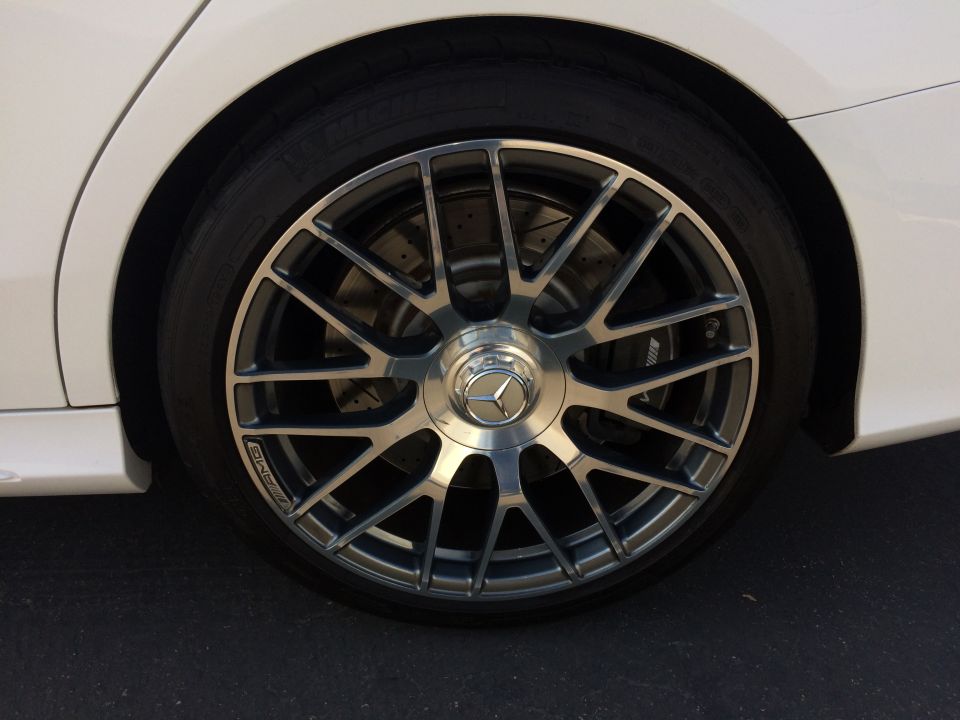White Mercedes-Benz C-Class wheel with AMG branding and drilled brake rotors