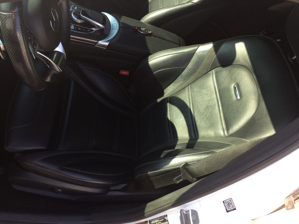 Black leather interior of a 2017 Mercedes-Benz C-Class, showing the driver's seat, steering wheel, and center console