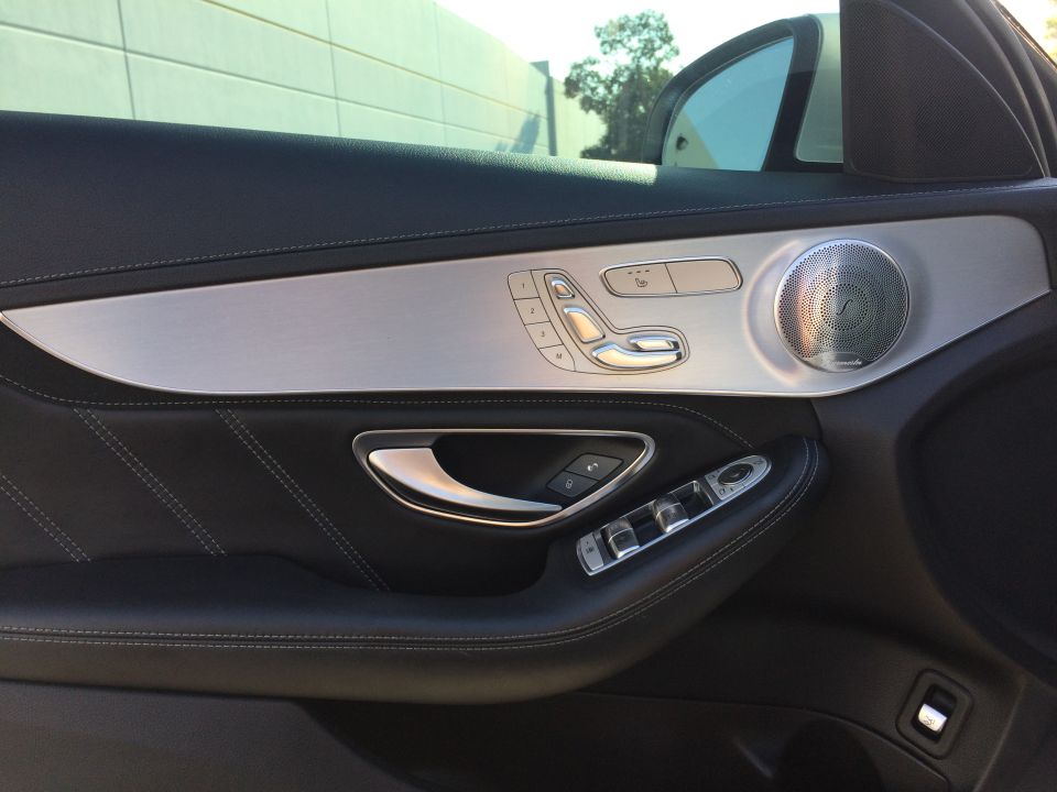 Interior door panel of a 2017 Mercedes-Benz C-Class showing seat controls, window switches, and speaker grille