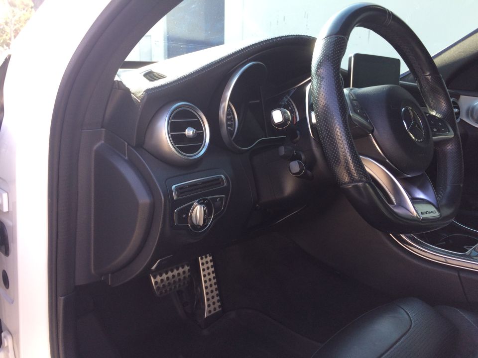 Interior of a 2017 Mercedes-Benz C-Class showing the dashboard, steering wheel, and pedals