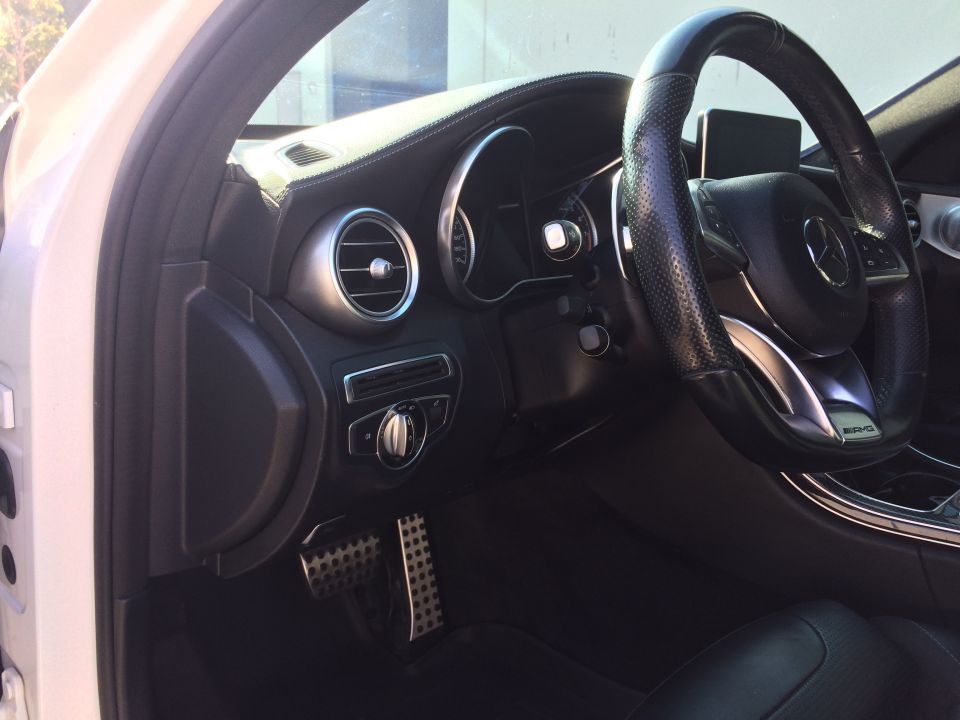 Interior view of a 2017 Mercedes-Benz C-Class showing the dashboard, steering wheel, and pedals