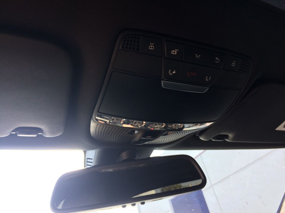 Overhead console with buttons and lights, plus rearview mirror inside a car