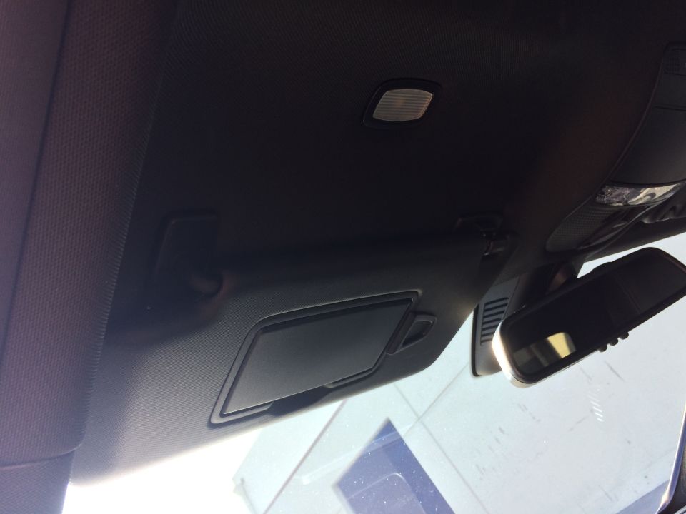 Interior shot of a car's ceiling, showing the visor, rearview mirror, and overhead lights
