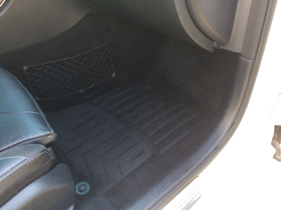 Black rubber floor mats and a net pocket on the passenger side floor of a car interior