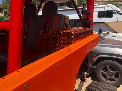 1992 Jeep Wrangler - Interior view of an orange off-road vehicle with racing seats and a roll cage, parked next to another vehicle.