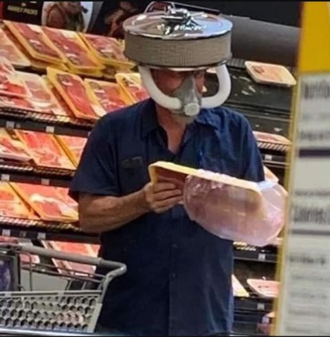 1990 Ford Bronco - Man in grocery store wears a helmet made of an air filter and a gas mask while shopping for meat.