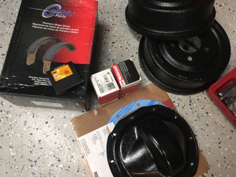 1998 Ford Ranger - Collection of automotive brake and axle parts, including new brake shoes and drums.