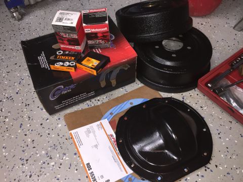 1998 Ford Ranger - Various automotive parts, including brake drums, brake shoes, and a differential cover, are laid out on a garage floor.