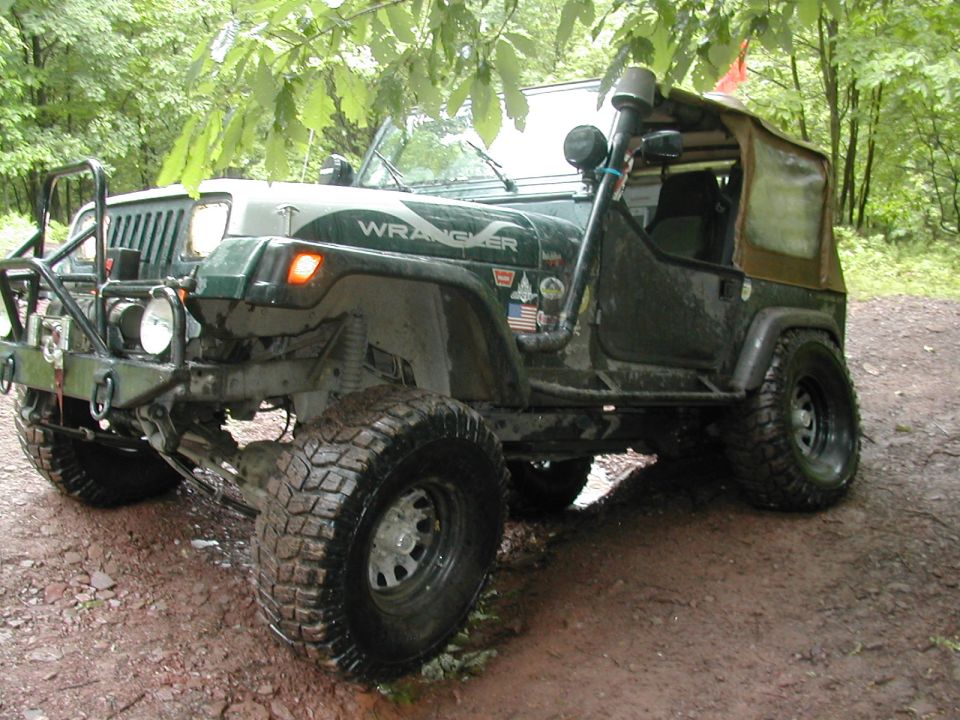 Green 1992 Jeep Wrangler with off-road tires and snorkel, parked on a dirt path