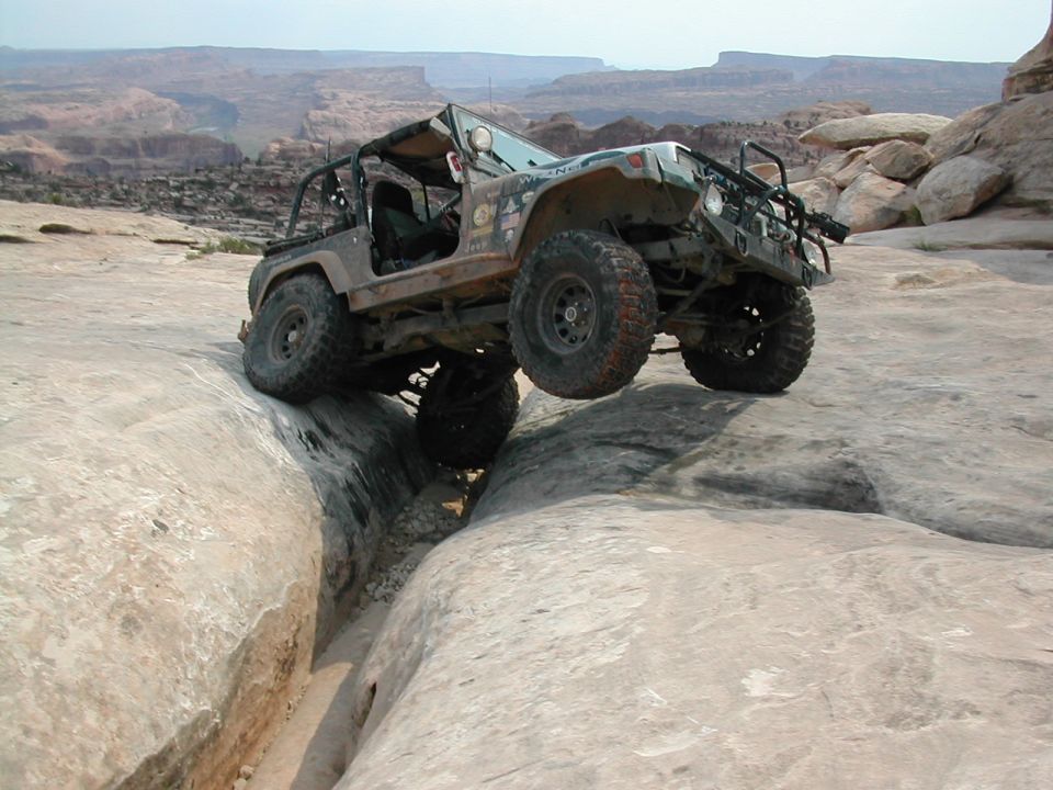 1992 Jeep Wrangler navigating a rocky canyon, front-right wheel lifted