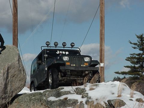 1992 Jeep Wrangler - Jeep Wrangler navigates rocky terrain covered in snow.