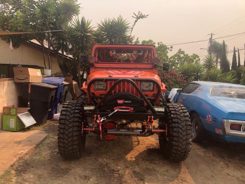 1992 Jeep Wrangler - This modified Jeep Wrangler features a winch and aggressive off-road tires, parked in a driveway next to another vehicle.