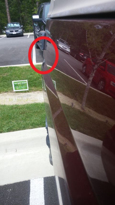 1996 Ford Bronco - Close-up of a side mirror on a parked vehicle, with other cars visible in the background.