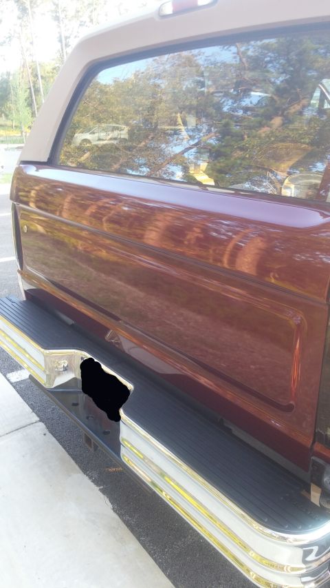 1996 Ford Bronco - A red Ford Bronco is partially visible from the rear, showing its bumper and side panel.