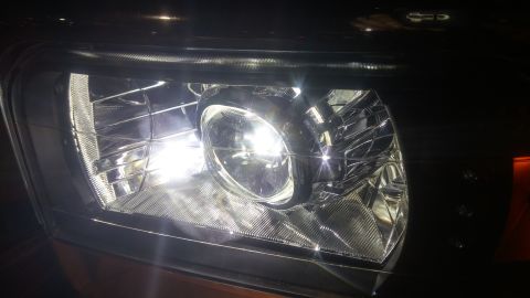 1996 Ford Bronco - A detailed view of a vehicle's headlight, showing its internal structure and bright illumination.