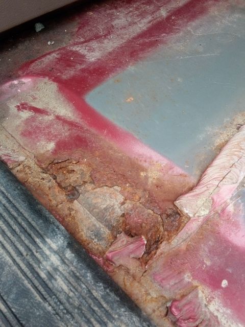 1994 Ford Bronco - This image shows significant rust and damage on a metal panel, with visible red and blue paint.