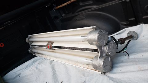 1965 Ford Mustang - A dual-tube fluorescent light fixture is shown resting on a tarp inside a vehicle's cargo area.