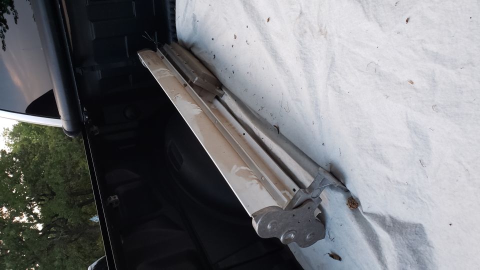Chrome trim piece with mounting brackets, resting on a white tarp