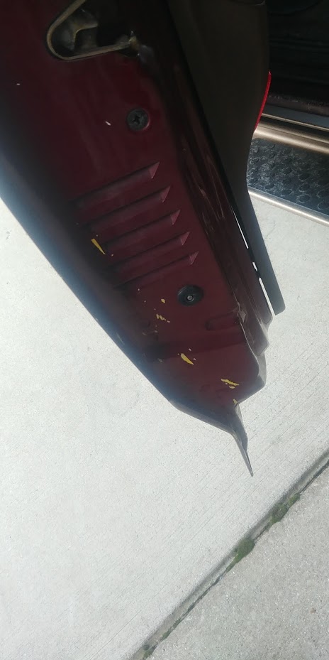 1996 Ford Bronco - Close-up of a red vehicle's door sill, showing vents and some paint damage.