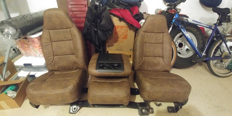Two brown bucket seats and a center console with cup holders and controls