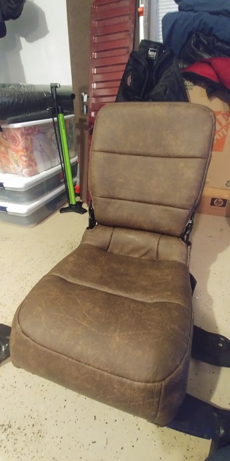 1996 Ford Bronco - A detached car seat sits on a concrete floor, surrounded by storage containers and other items in a garage.