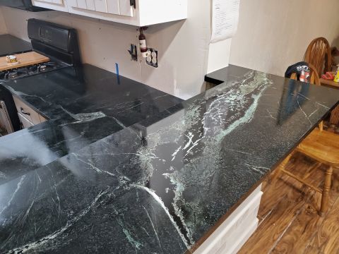1980 Yugo Vega - Kitchen countertop with dark green and white veining, visible stove and cabinets.