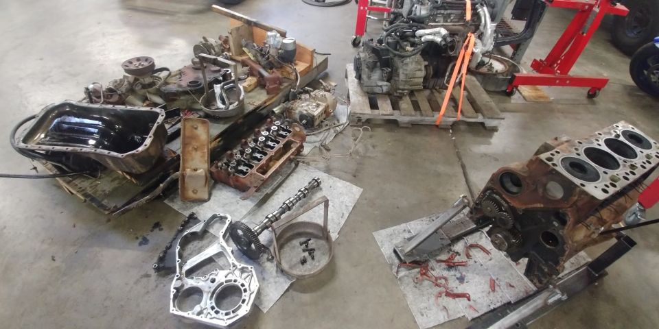 Disassembled engine block and oil pan on a concrete floor