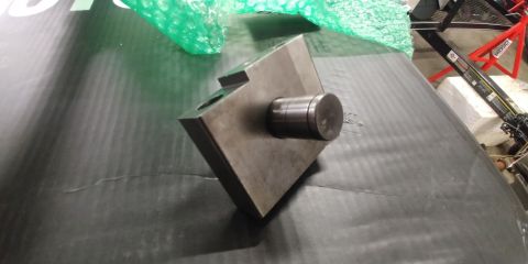1996 Ford Bronco - A metal part with a cylindrical pin is shown on a dark surface, with some green bubble wrap in the background.