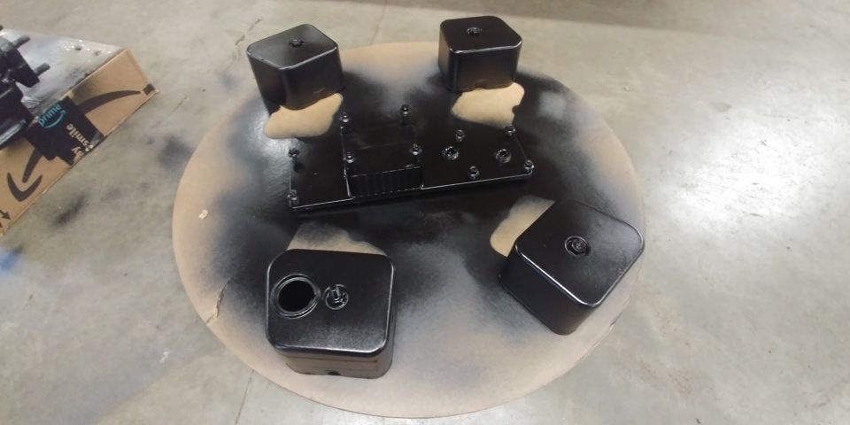 Black painted engine parts on a turntable with spray paint overspray