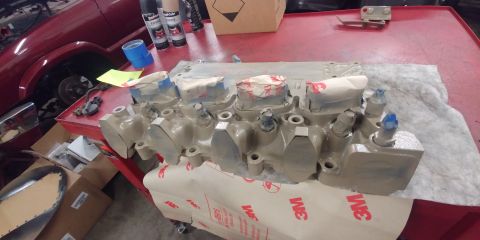 1996 Ford Bronco - Engine cylinder head is prepped and painted on a workbench with spray cans nearby.