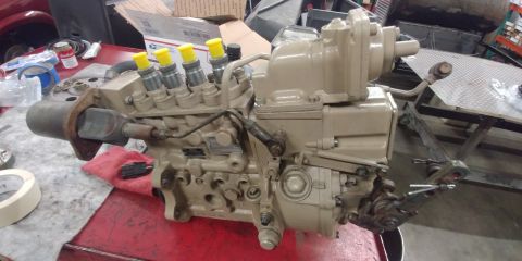 1996 Ford Bronco - A tan diesel injection pump with yellow capped injectors sits on a red workbench.
