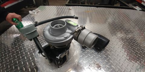 1996 Ford Bronco - A turbocharger is shown on a diamond plate surface, with a hand holding a soda can nearby.