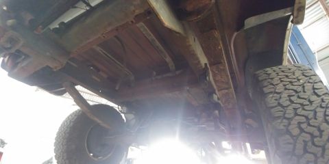 1996 Ford Bronco - The underside of a vehicle shows significant rust and wear, with large off-road tires visible.