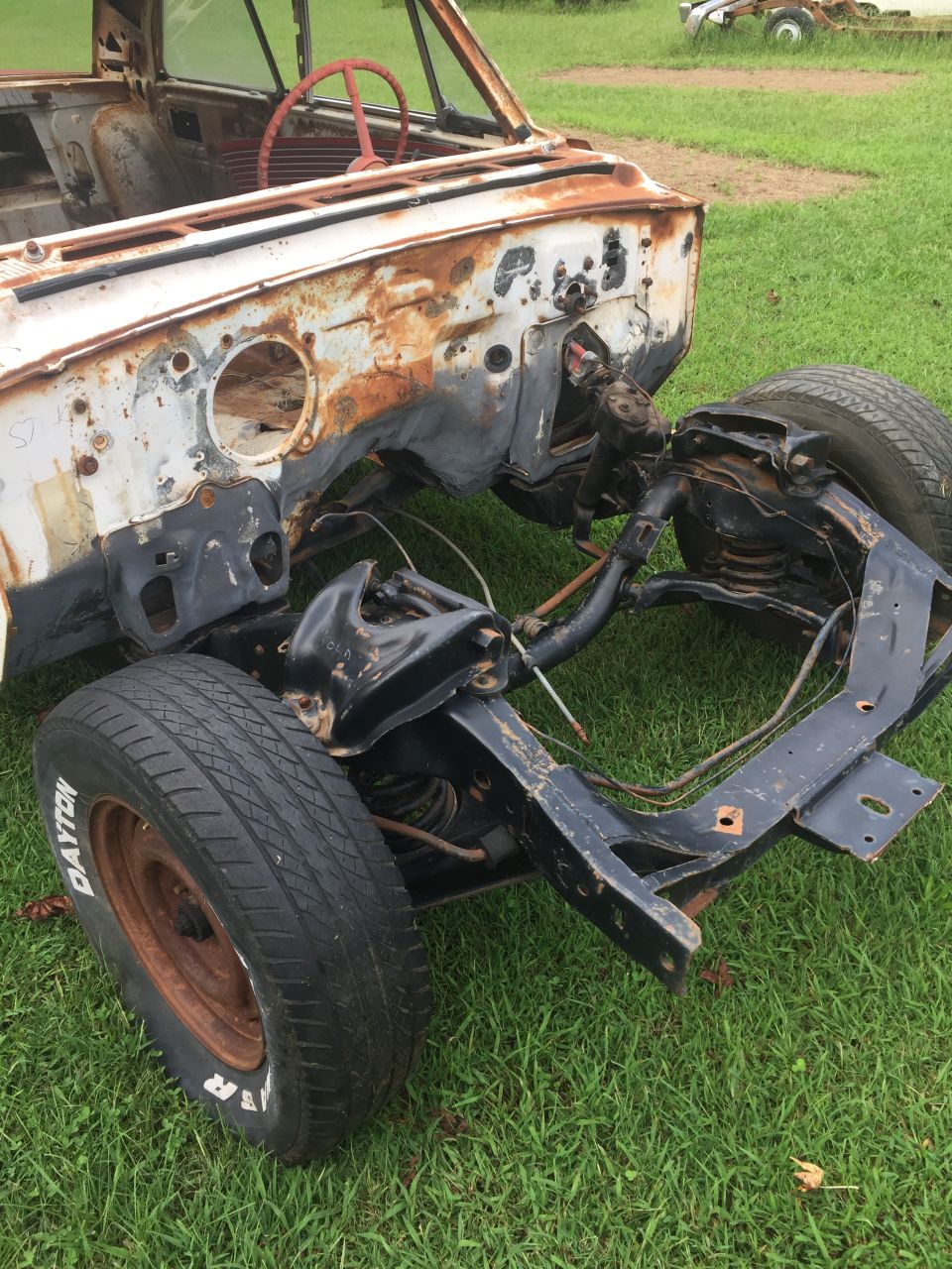 rusted car chassis with front suspension and tires, steering whe ...