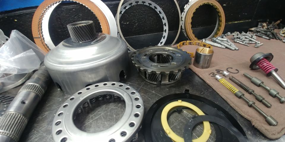 Various transmission components including gears, clutches, and springs laid out on a workbench