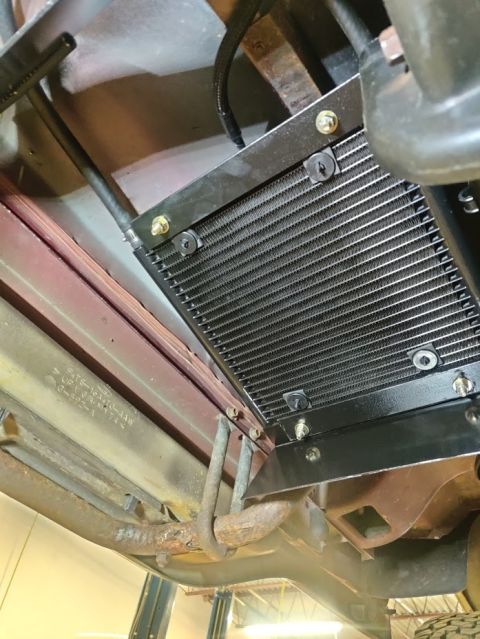 1996 Ford Bronco - Close-up view of a transmission cooler installed on the underside of a vehicle.