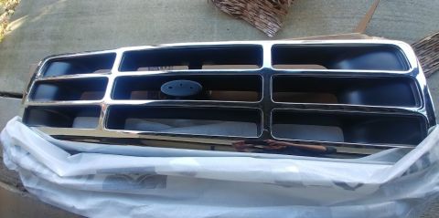 1996 Ford Bronco - This is a chrome grille, possibly from a 1996 Ford Bronco, shown on a surface.