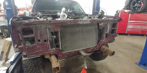 1996 Ford Bronco - Front end of a maroon SUV is disassembled for repair or modification, revealing the radiator and a turbocharger.
